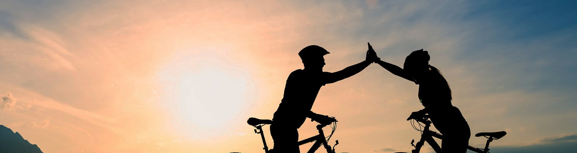 Dos ciclistas con los brazos elevados con luz que brilla hacia el espectador