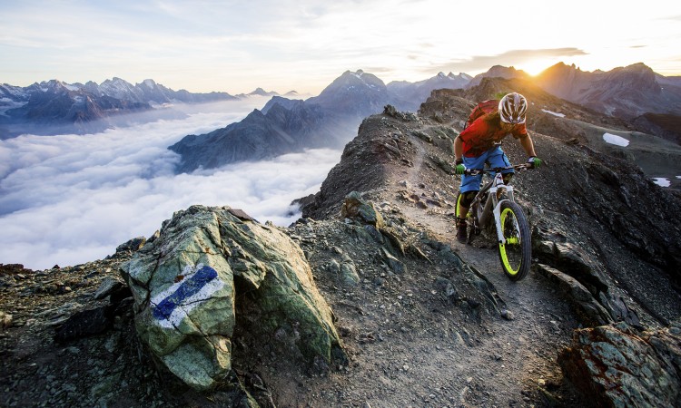 Cima de montaña con luz de la mañana con un ciclista en bicicleta de montaña
