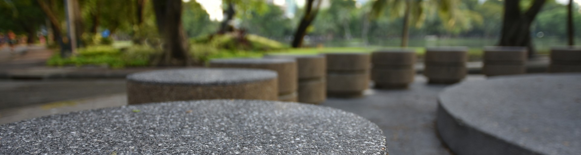 Circular ordered stone bollards with a background of grass and tree-trunks