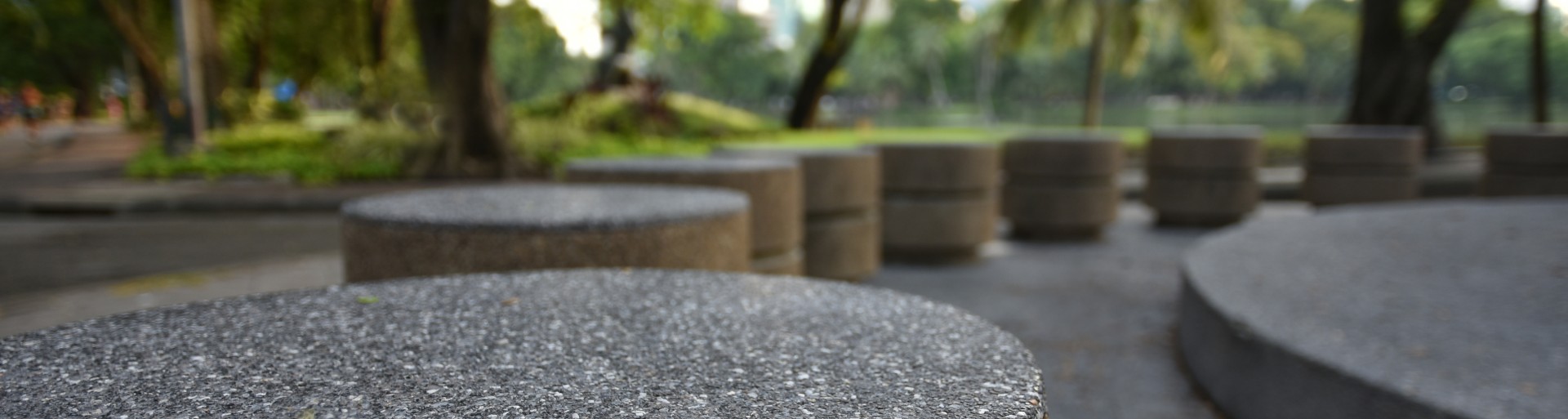 Bolardos circulares de piedra ordenados con fondo de hierba y troncos de árboles