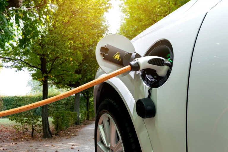 Carga de movilidad electrónica Cable de carga naranja enganchado en la abertura del depósito de un coche blanco