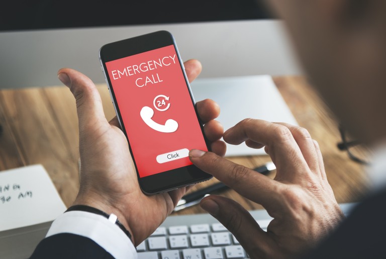 Centro de toxicología Mano sosteniendo un teléfono inteligente con una pantalla de color rojo-blanco que muestra las letras de la llamada de emergencia